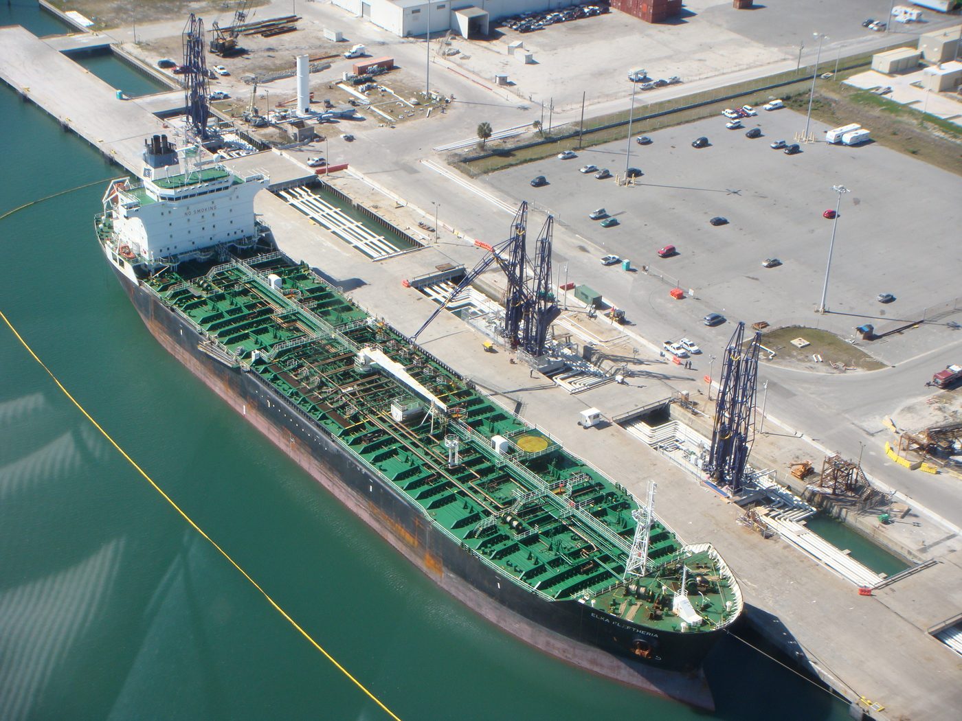 Tanker langs een steiger met laadarmen, van bovenaf gezien