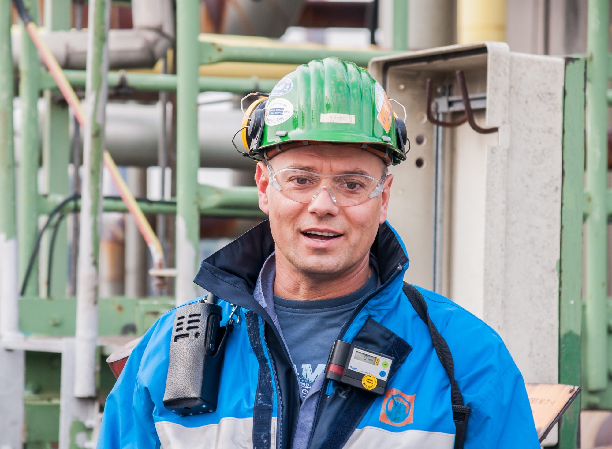 Operator met helm, veiligheidsbril en gasdetector op een raffinaderij